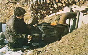 Neva starts a fire to smoke meat and fish.